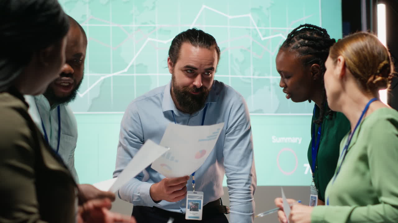 Diverse group of professionals review files and performance metrics