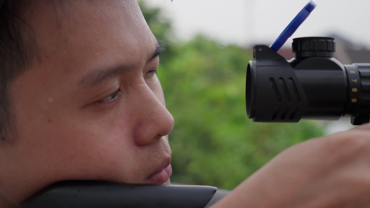 Asian sniper with scoped pcp air rifle shooting in slow motion