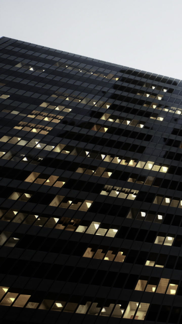 Office building at dusk with lit windows and dark sky overhead