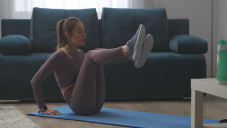 Una-Mujer-Deportiva-Está-Ajustando-El-Rastreador-De-Ejercicios-Y-Haciendo-Abdominales-En-La-Sala-De-Estar,-Entrenando-En-Casa-A-Una-Joven-Y-Delgada-Dama-Atlética-Haciendo-Ejercicio-Físico-Para-Una-Buena-Forma-Del-Cuerpo