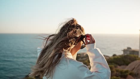 Nähert-Sich-Einem-Freigeistigen-Mädchen,-Das-Den-Sonnenuntergang-Von-Den-Felsen-Am-Meer-Aus-Genießt