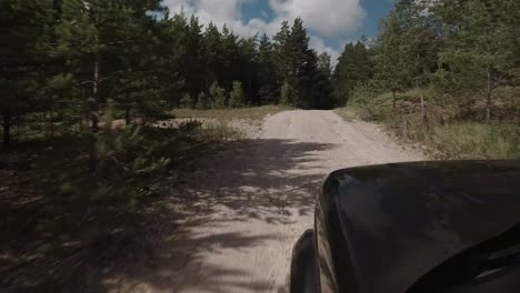 Car-driving-through-puddle-and-splashing-water-on-a-gravel-road