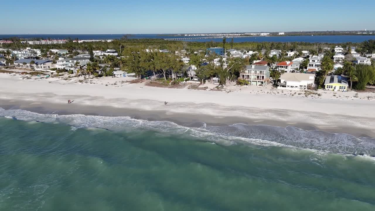 Luftfoto av en tropisk strand med hvit sand og havbølger