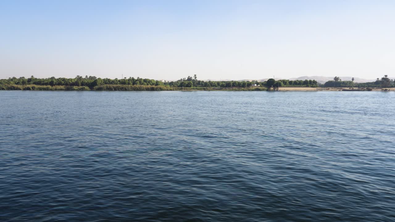 Nile river flowing peacefully with the egyptian farmland in the background