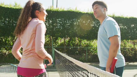video de una feliz pareja biracial jugando al tenis en la cancha