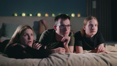 family watching a movie in bed at night