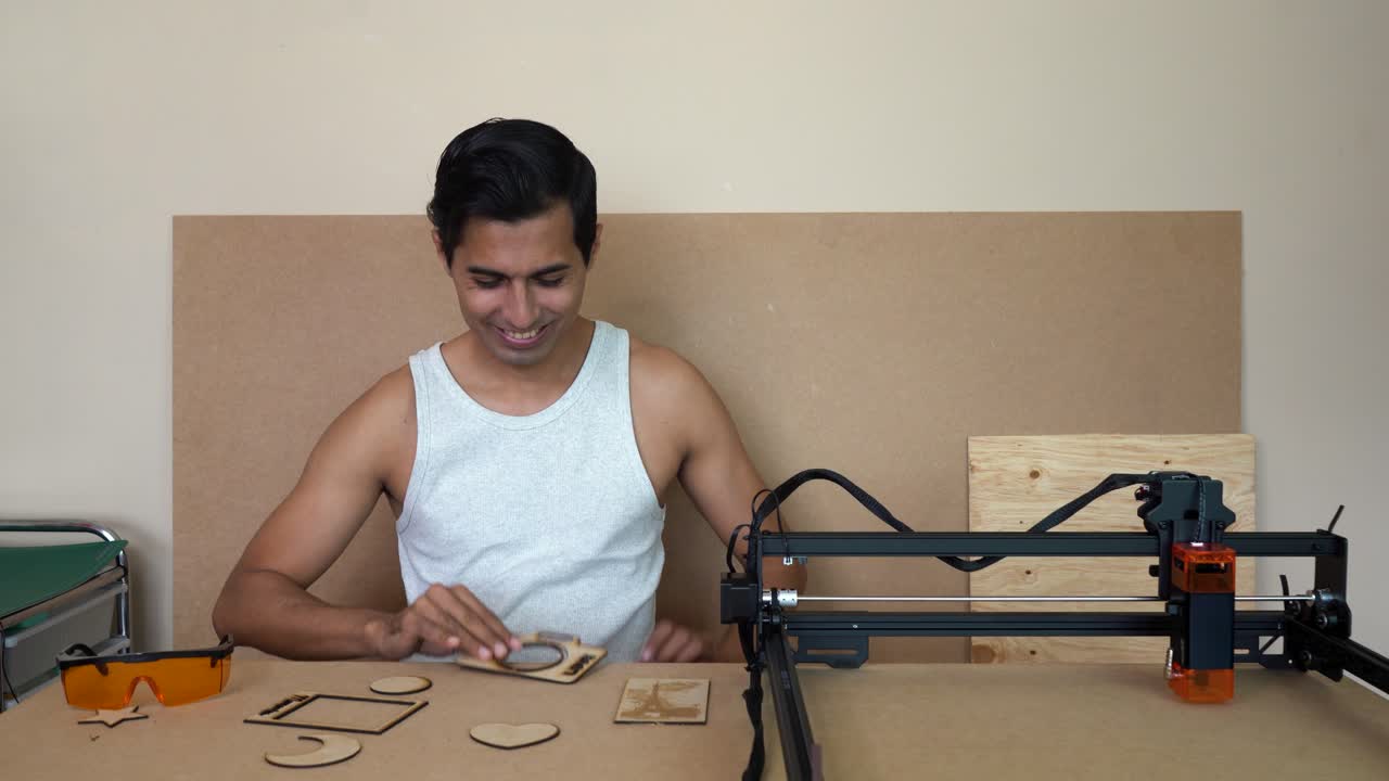 Homem cortando MDF com laser de diodo, sorrindo criativamente em local fechado