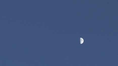 Filming with a drone at night at 167mm of the crescent moon, the entire background is dark blue and in the middle of the moon we can see its spots, it moves from left to right, in slow motion