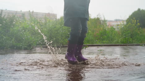 un niño saltando en un charco en un día de lluvia