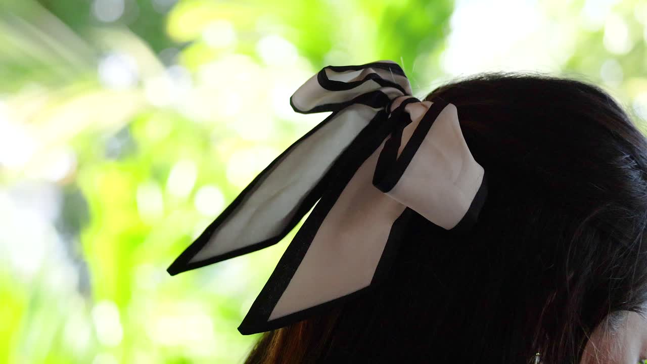 Close-up of a ribbon in a woman's hair against a vibrant, sunlit background in Phuket, Thailand
