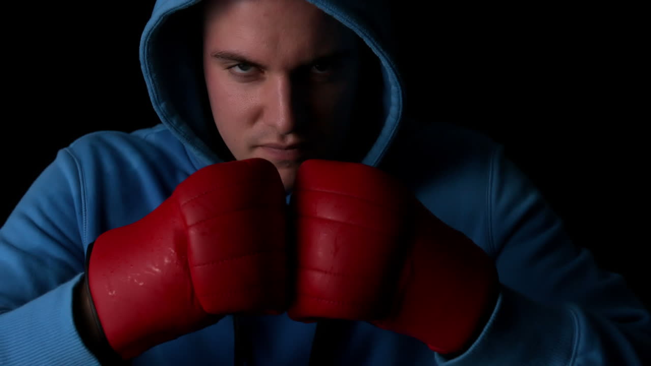 boxeador duro golpeando puños juntos con guantes rojos