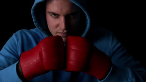 boxeador duro golpeando puños juntos con guantes rojos