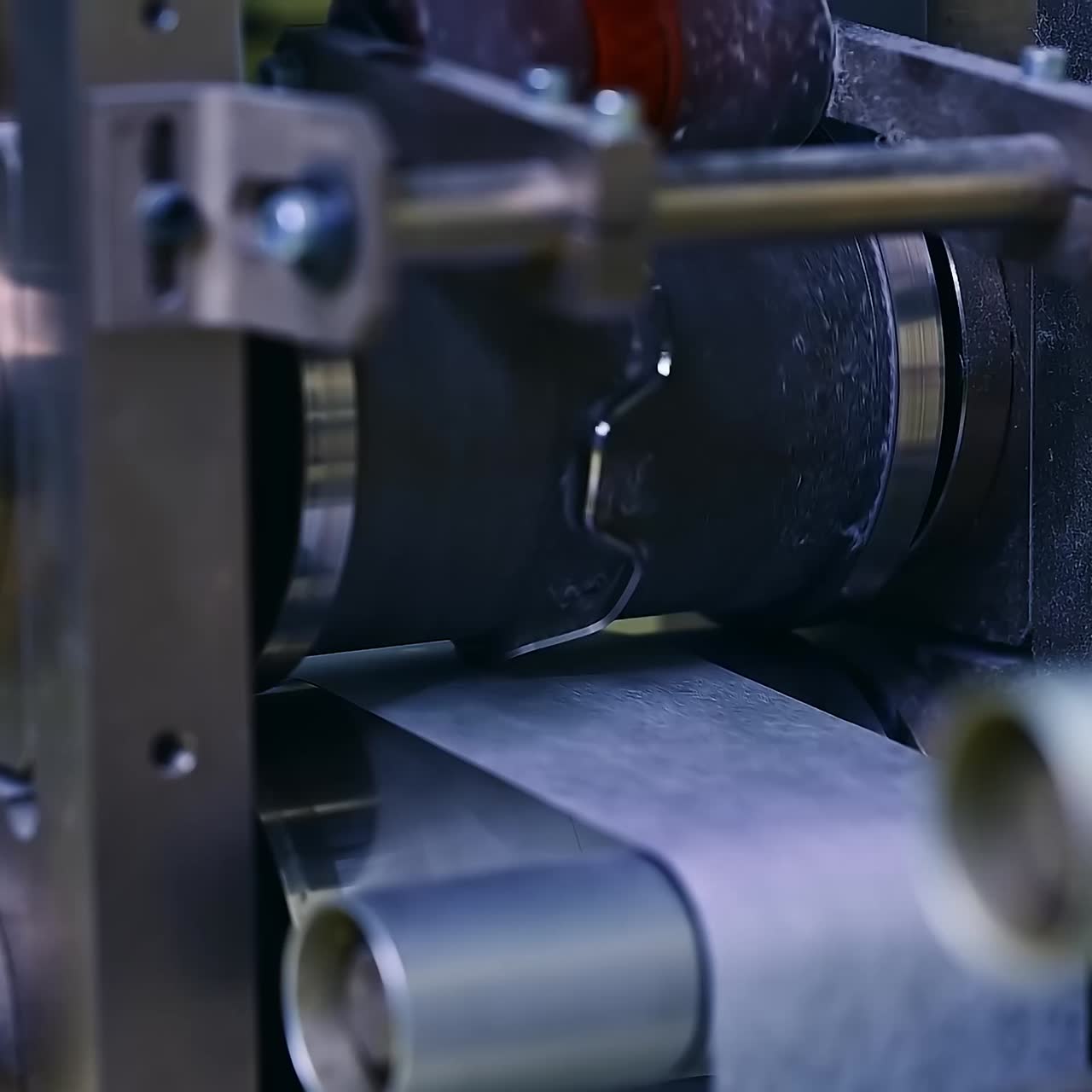 Technological equipment for producing diapers at the factory. Shafts and rollers spinning at conveyor line. Close up