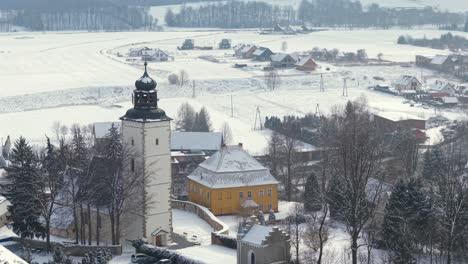 aerial drone orbit the church of the immaculate conception in lomnica, poland, on snow covered winter day in town