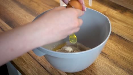 woman's hand breaking an egg into a bowl