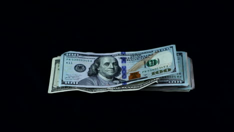 stack of hundred dollar bills falling in black background - studio shot