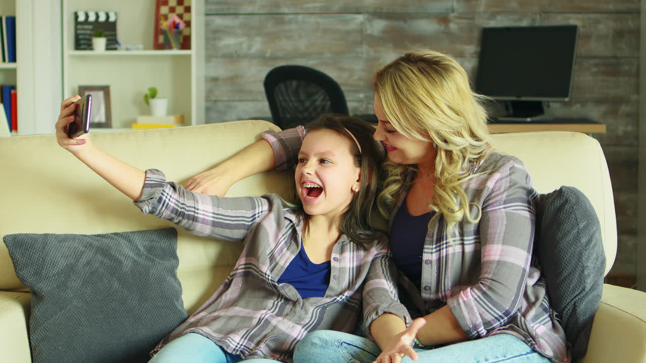 즐거운 어머니와 딸이 셀피를 찍고 있습니다.