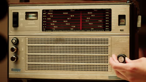 person adjusting an old vintage radio