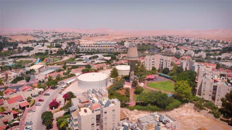 aerial view of a town with a prominent water tower and reservoir, surrounded by residential buildings and distant desert mountains
