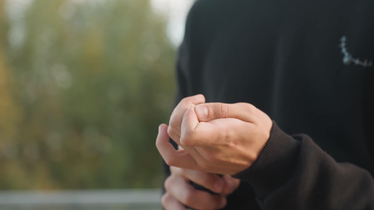 Le mani ispezionano l'attrezzatura. Una persona fissa il trapano alla ringhiera. Un individuo concentrato esegue attentamente un'ispezione di sicurezza finale. Un operaio calmo testa e fissa il trapano vicino agli alberi nelle ore serali.