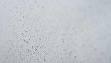 close-up view of a rainy glass as rain drops hits a window during a gloomy and overcast weather