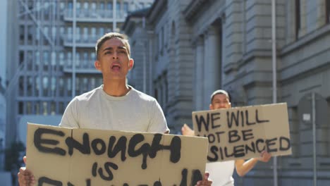 two mixed race men on a protest march holding placards raising hands and shouting