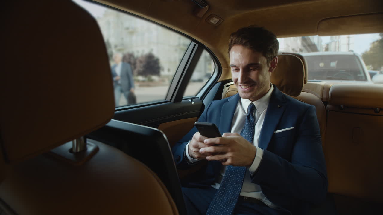 hombre feliz profesional mensaje de escritura en el teléfono inteligente en el coche de negocios.