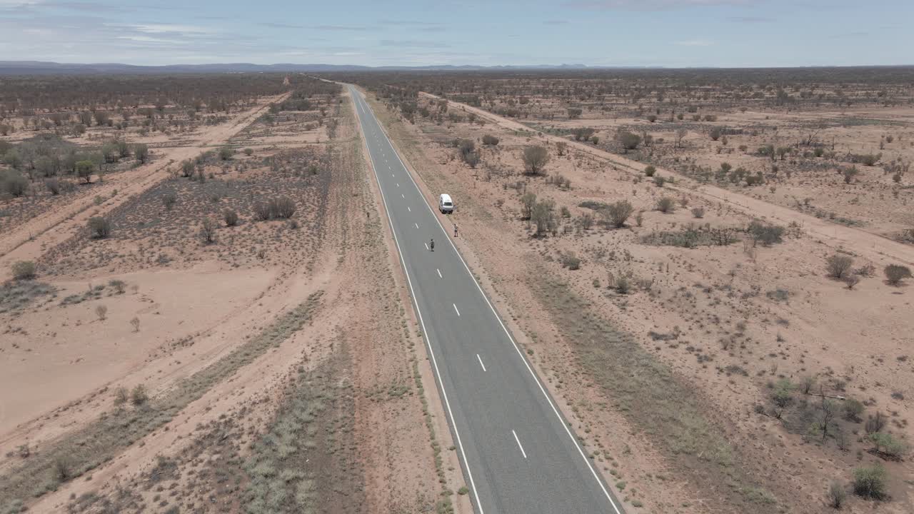 People On Pavement Country Road With White Van Parked In Remote Arid Desert In Northern Territory, Australia. - Aerial Drone Shot