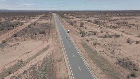 people on pavement country road with white van parked in remote arid desert in northern territory, australia. - aerial drone shot
