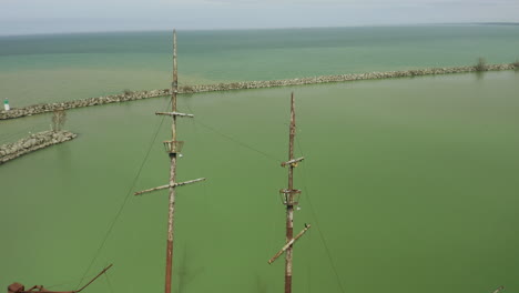 Rusty red shipwreck stuck in shallow green water