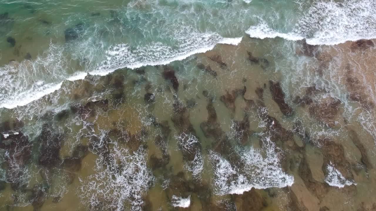Acqua turchese tropicale con rocce visibili sotto le onde, vista aerea con drone.