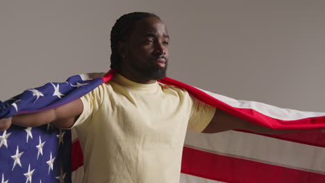 studio portrait shot of man wrapped in american flag celebrating 4th july independence day 1