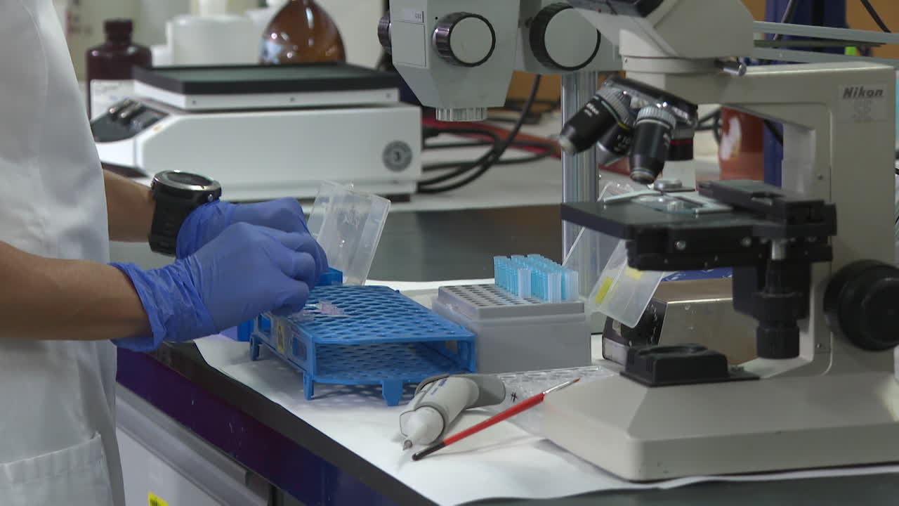 científico que trabaja en un laboratorio con microscopio y tubos de ensayo