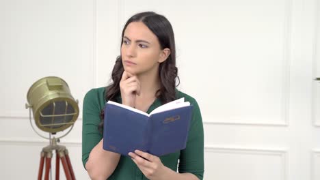 mujer india pensativa leyendo un libro