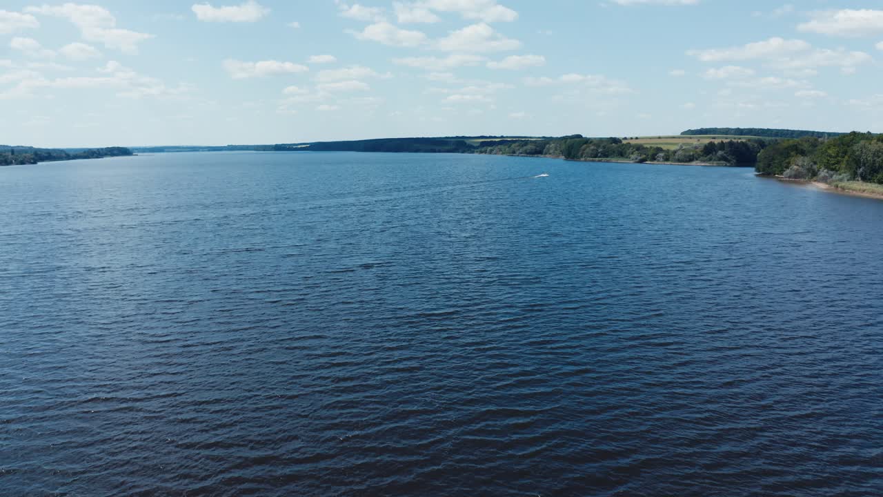 Wide river with blue water. Flying over the beautiful lake in daytime. Panoramic view of nature. Aerial view.