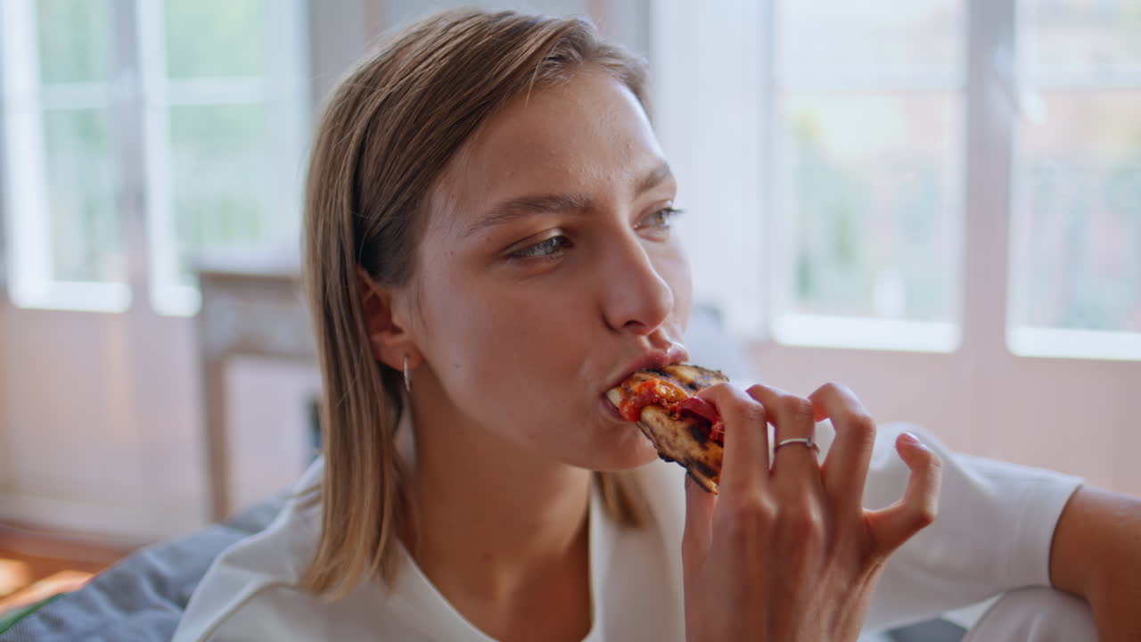 Hungry girl eating pizza talking interlocutor at domestic atmosphere closeup