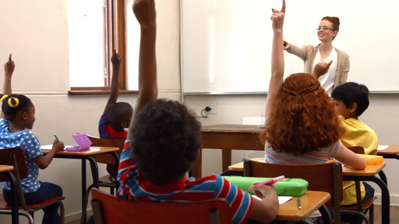 niños de la escuela levantando las manos en clase