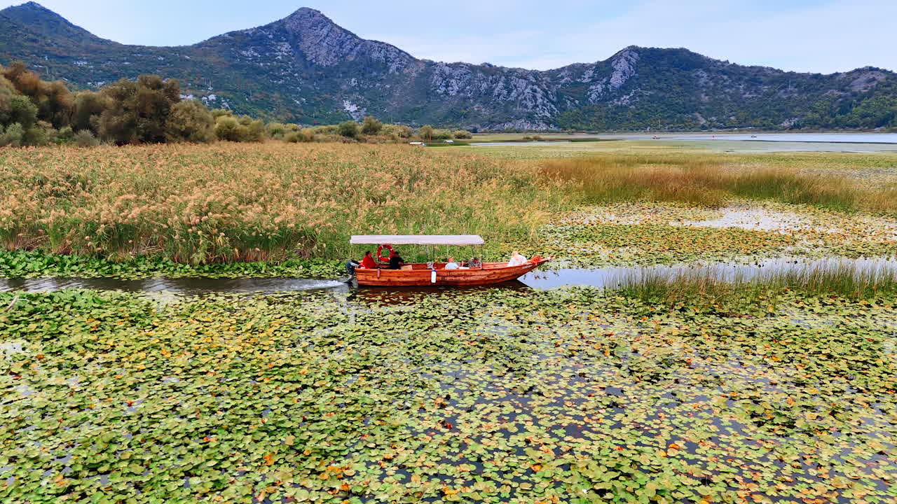 Ulcinj, Montenegro, 14 August 2025: Boat entering open lake. A wooden boat exits a reed channel and approaches the open waters of the lake