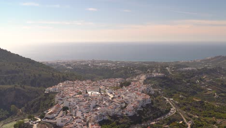 panorámica derecha a través de un pueblo encalado en la cima de una colina con el océano a lo lejos