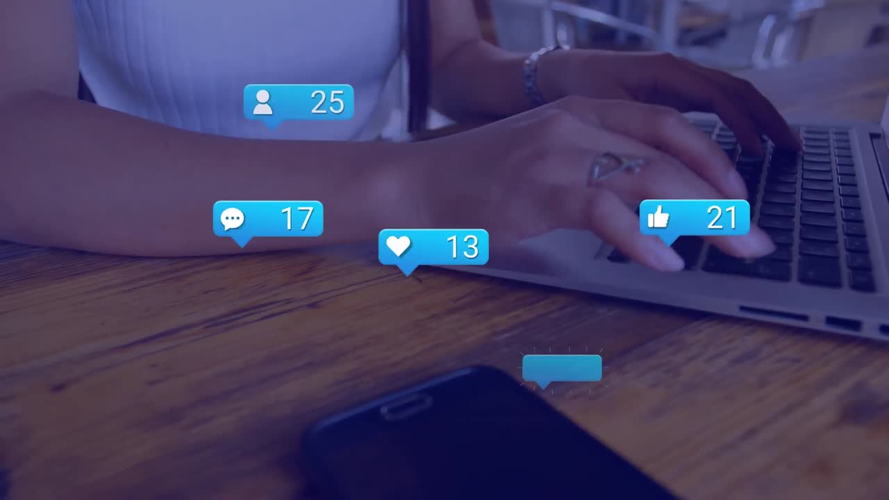 Animation of social media reactions over hands of biracial girl using laptop at school