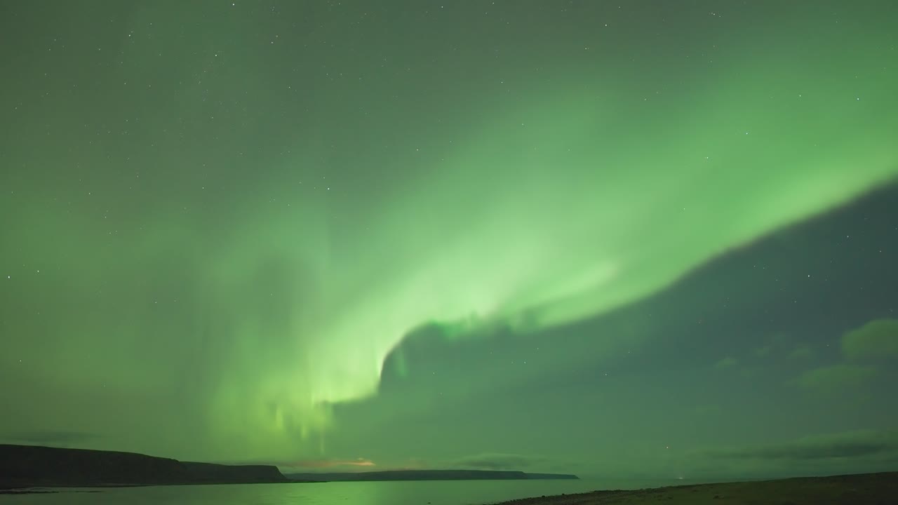 un video en timelapse de las hipnotizantes luces del norte bailando sobre un fiordo tranquilo en una oscura noche de invierno