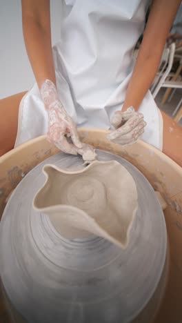 a person's hands shaping clay on a pottery wheel