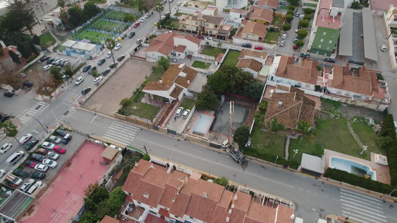 Tomada aérea rotativa de uma cidade em Málaga, Espanha: edifícios, casas e um canteiro de obras com um guindaste.