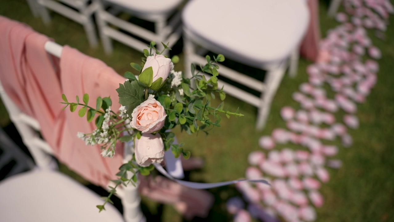 Fiori e sedie sono allestiti per una cerimonia in un giardino. Tessuti e decorazioni rosa creano un bell'aspetto per l'evento. L'erba è verde. L'allestimento è pronto per gli ospiti