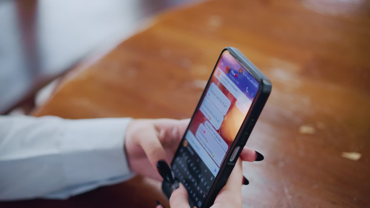 vista parcial de una mujer hablando por teléfono con su ex, con la luz reflejada en la superficie de la mesa, texto y emojis visibles en la pantalla en una conversación personal e íntima