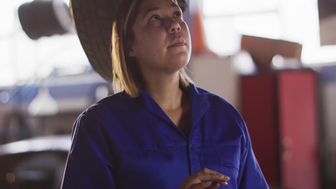 디지털 태블릿을 사용하는 여성 기계가 자동차 서비스 스테이션에서 자동차를 검사합니다.