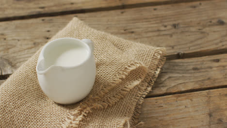 video of glass jug of milk on wooden background