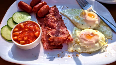 continental breakfast on plate, eggs bacon beans cucumber and sausage