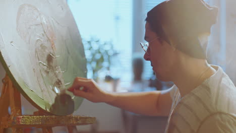 artist painting on canvas with palette knife in sunlit studio