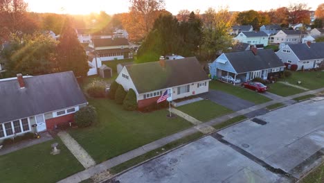 suburban neighborhood with single-family homes and an american flag at sunset